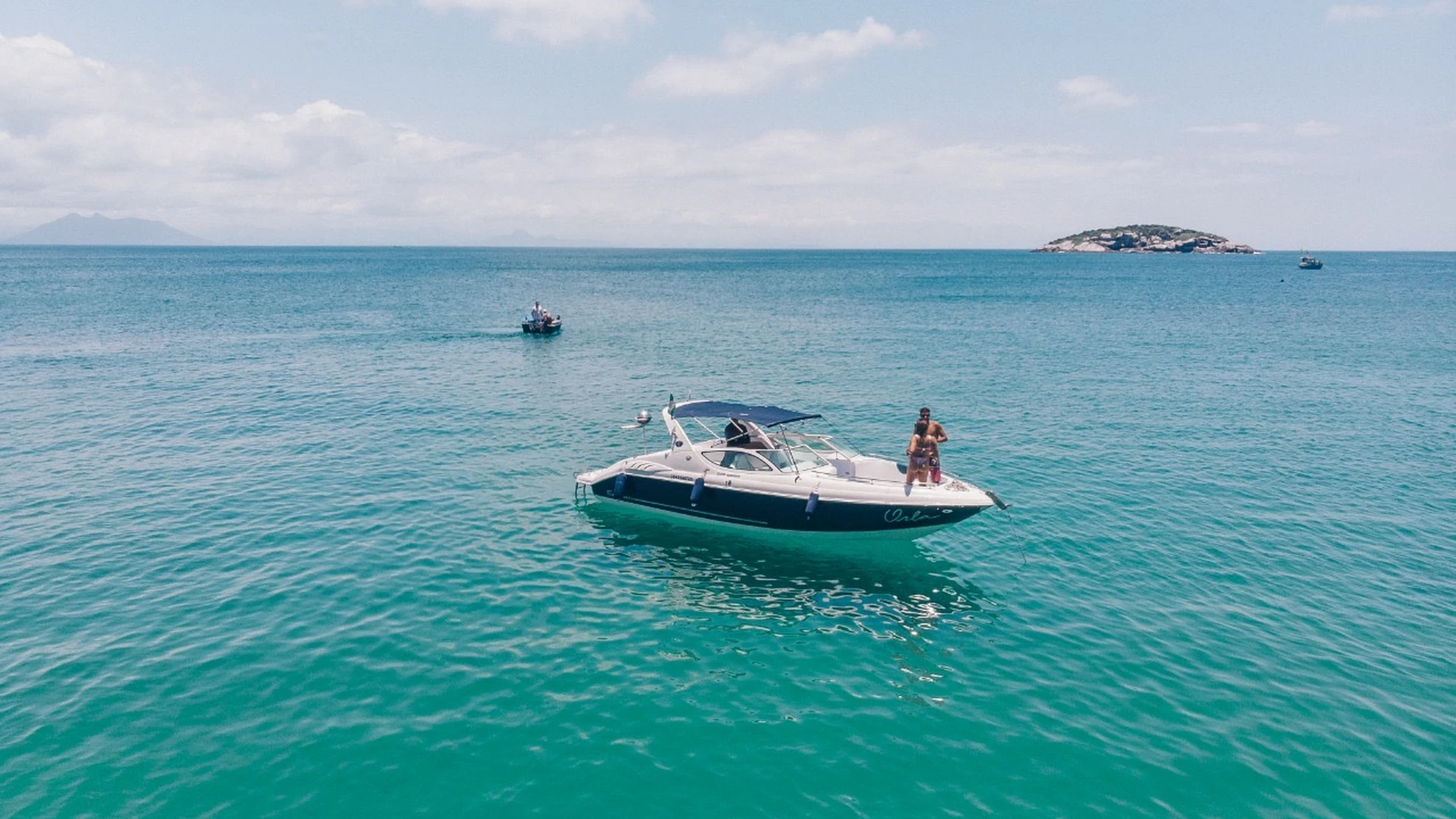 Lancha ancorada em mar turquesa com ilha ao fundo em Búzios